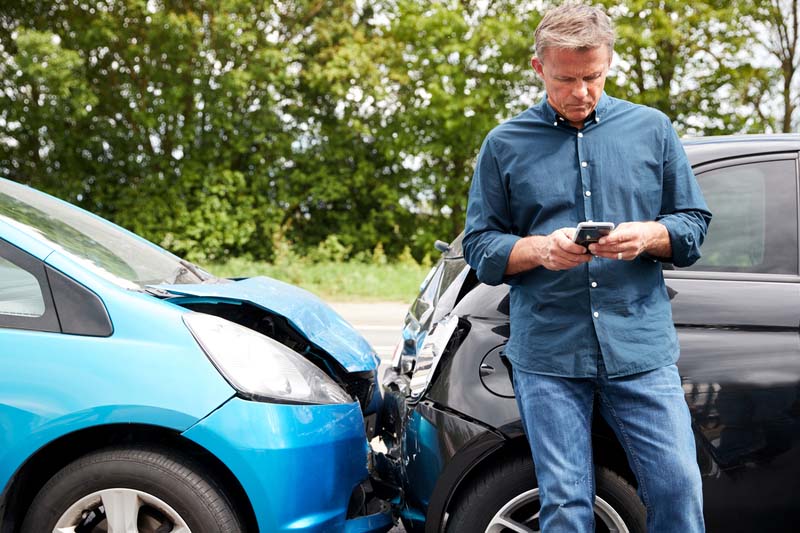 Mature Male Motorist Involved In Car Accident Calling Insurance Company Or Recovery Service